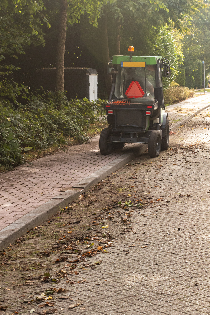 Street sweeper vehicle cleaning sidewalk edges in Almere
